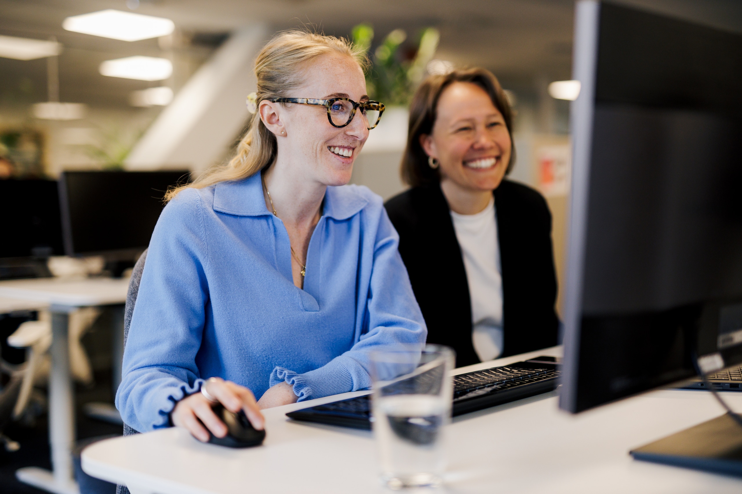 Två kvinnor sitter vid en datorskärm och går igenom kundens implementering